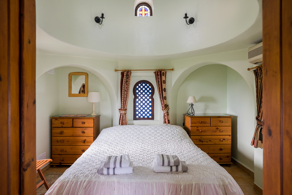 Imagen de dormitorio principal exótico de tamaño medio sin chimenea con paredes verdes y suelo de baldosas de terracota