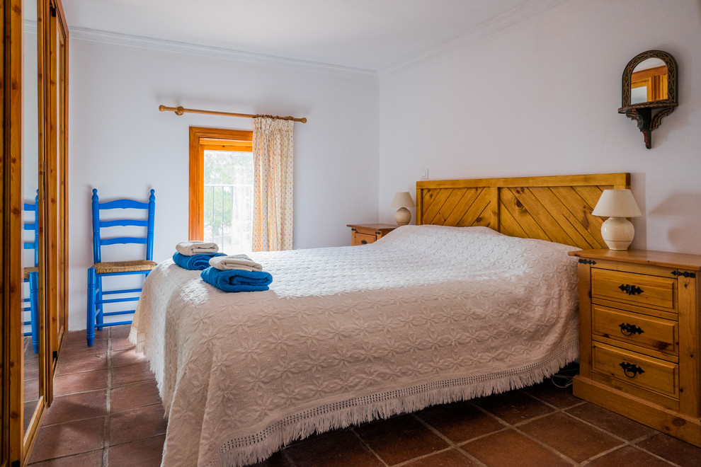 Esempio di una camera degli ospiti mediterranea di medie dimensioni con pareti bianche, pavimento in terracotta e nessun camino