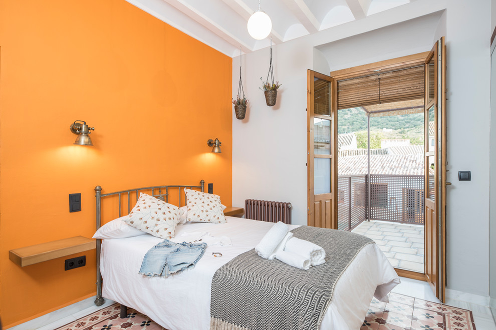 Idées déco pour une chambre grise et rose méditerranéenne avec un mur orange et un sol multicolore.