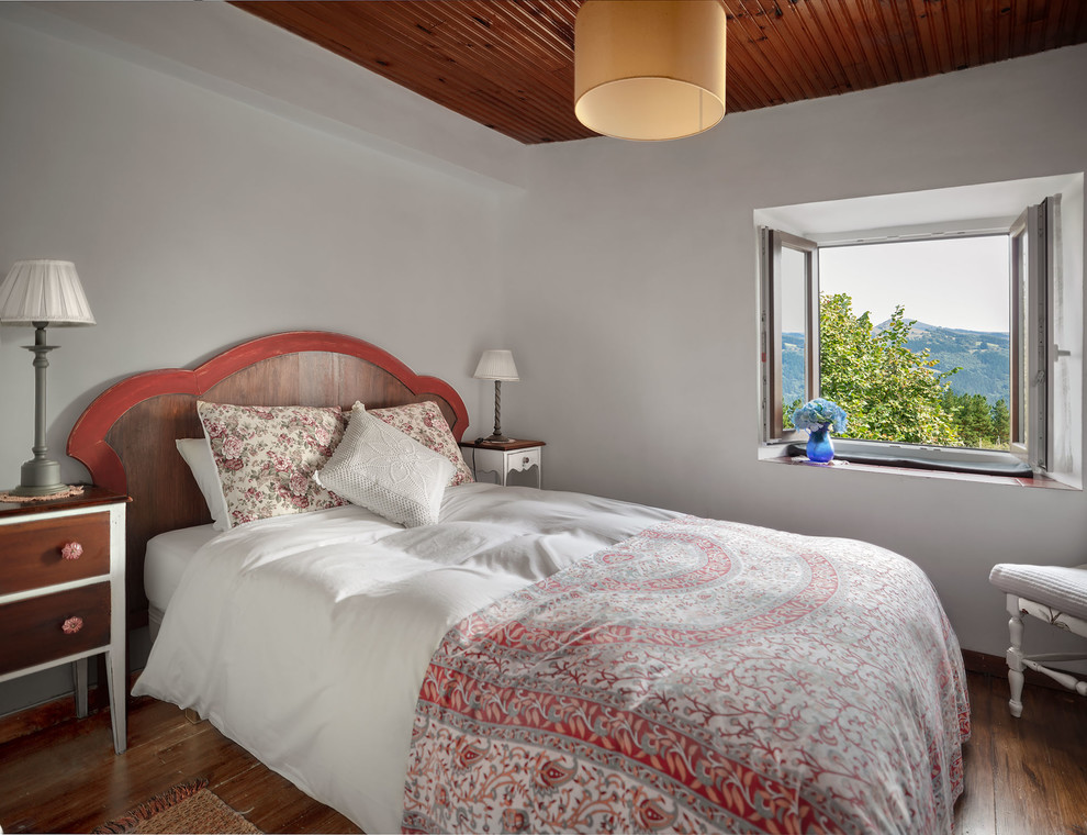 Imagen de habitación de invitados rural de tamaño medio con paredes blancas, suelo de madera oscura y suelo marrón