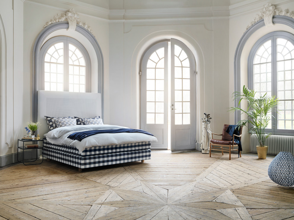 Imagen de dormitorio tipo loft tradicional grande con paredes blancas y suelo de madera clara