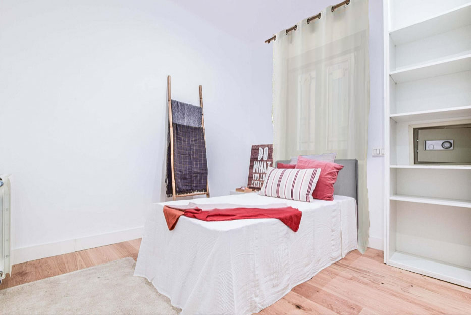 Modelo de habitación de invitados gris y blanca y blanca minimalista de tamaño medio con paredes blancas, suelo laminado y suelo marrón