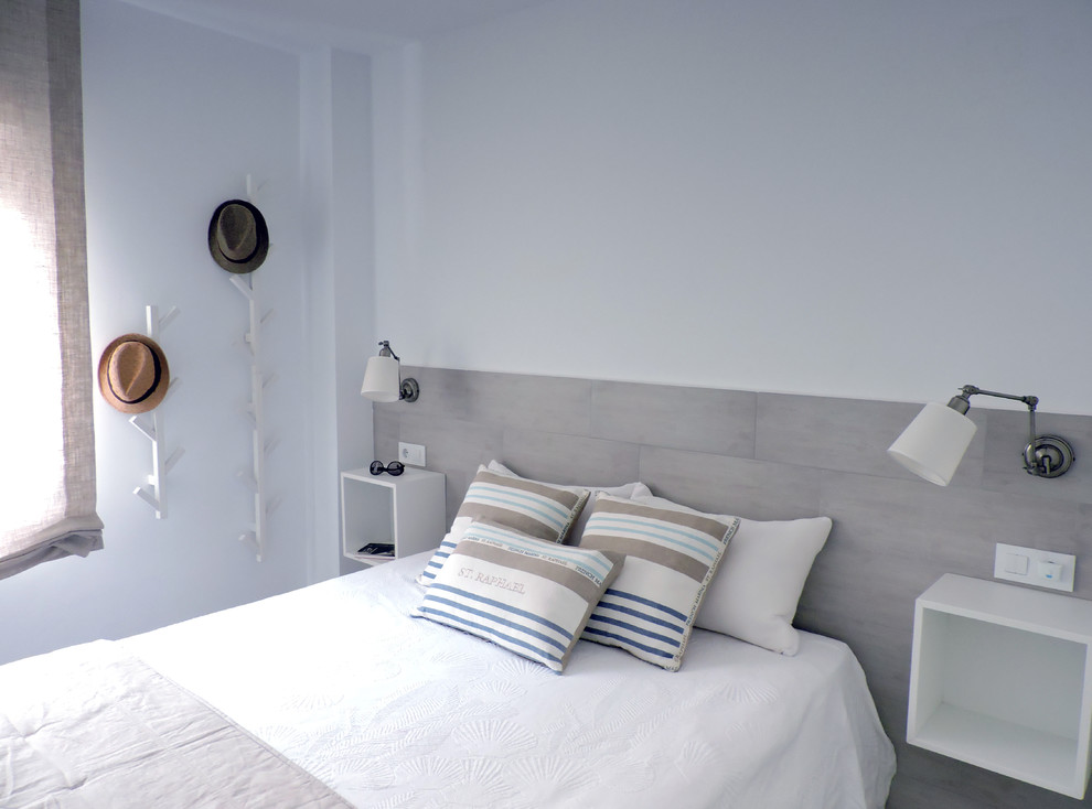 Modelo de dormitorio principal costero pequeño con paredes blancas, suelo de baldosas de cerámica y suelo beige