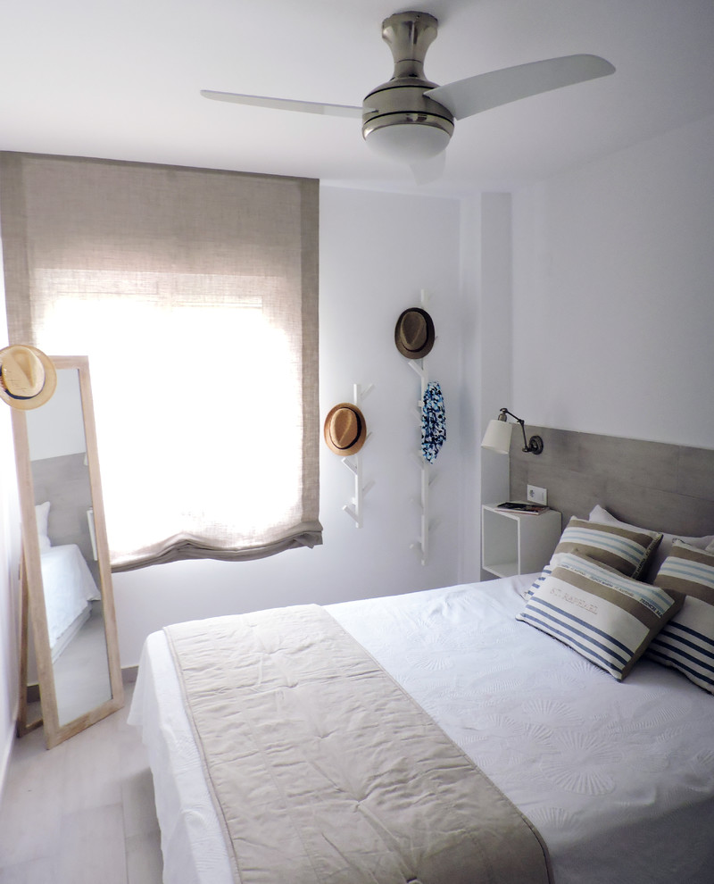 Foto de dormitorio principal costero pequeño con paredes blancas, suelo de baldosas de cerámica y suelo beige