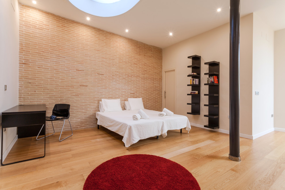 Diseño de dormitorio principal urbano grande sin chimenea con paredes beige y suelo de madera clara