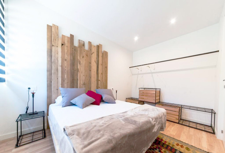 Inspiration for a medium sized industrial master bedroom in Other with white walls and light hardwood flooring.