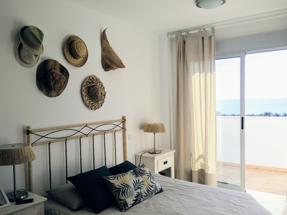 Ejemplo de dormitorio principal costero de tamaño medio con paredes blancas, suelo de baldosas de cerámica y suelo beige