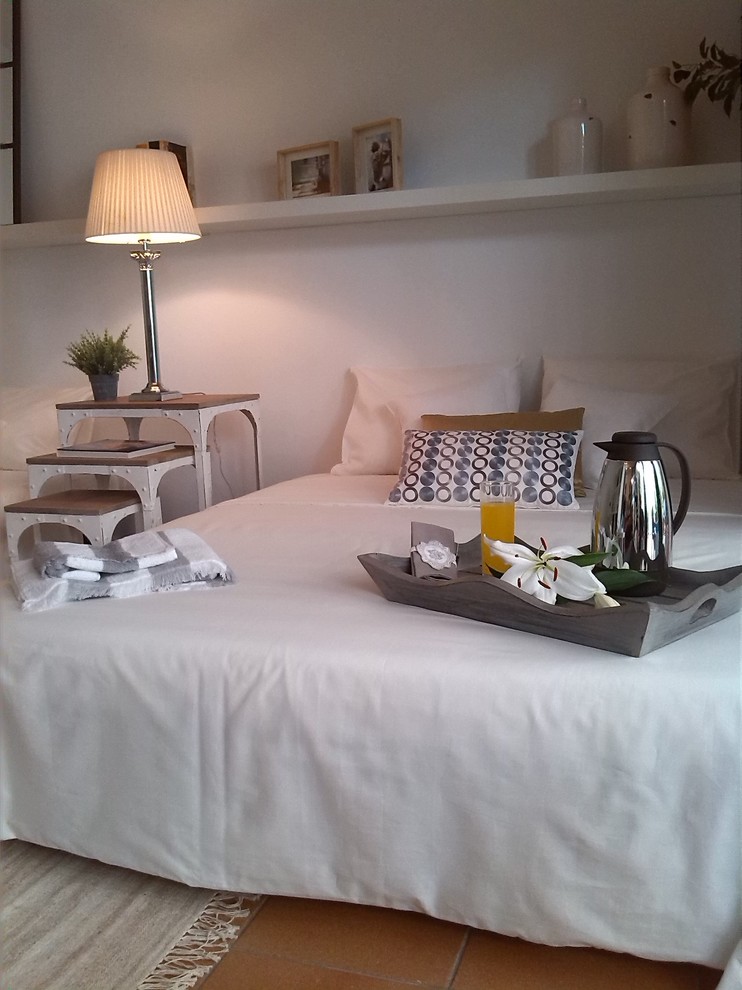 Ejemplo de dormitorio principal mediterráneo de tamaño medio sin chimenea con paredes blancas y suelo de baldosas de cerámica
