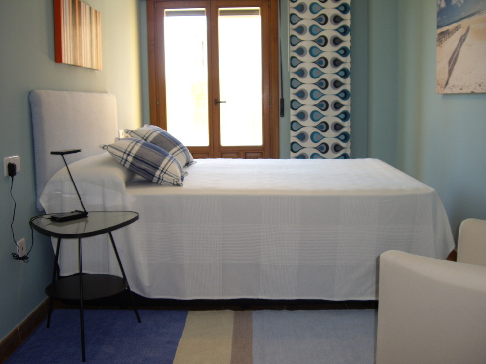 Imagen de dormitorio principal actual de tamaño medio con paredes azules, suelo de baldosas de cerámica y suelo marrón