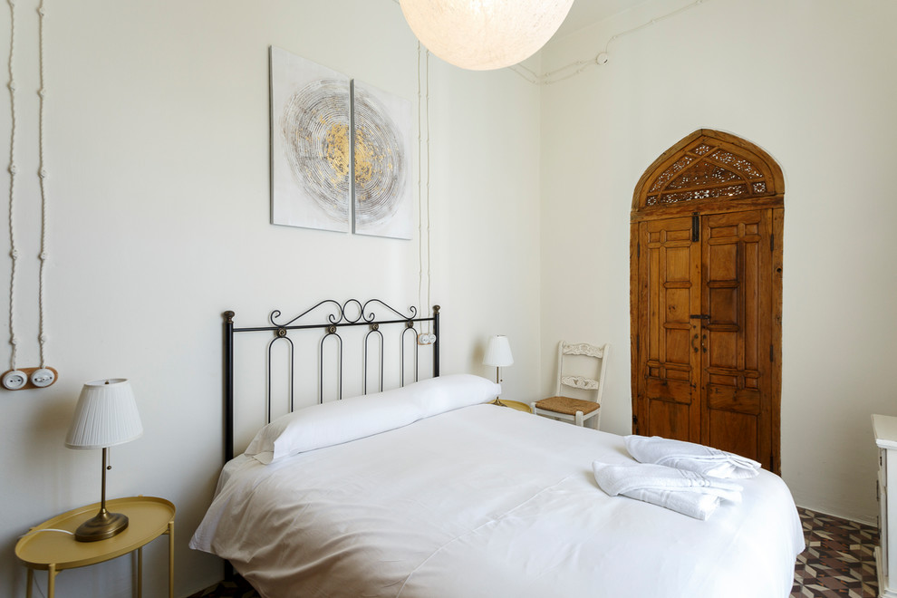 Esempio di una camera da letto mediterranea con pareti bianche e pavimento multicolore