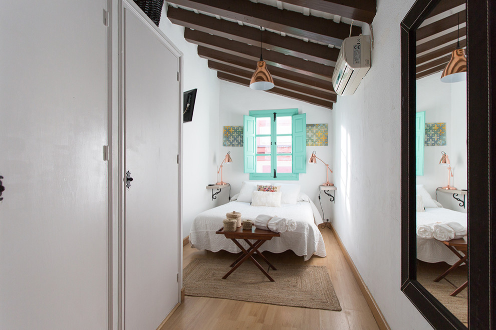 Example of a small tuscan master light wood floor bedroom design in Seville with white walls and no fireplace