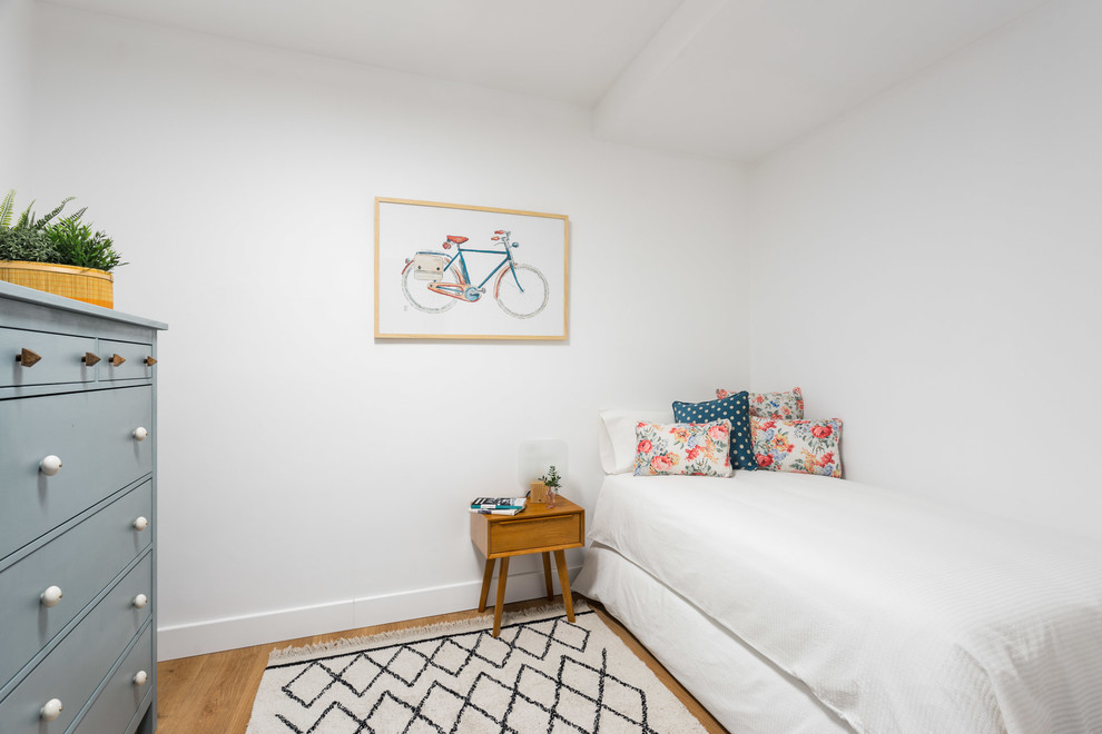 Ejemplo de habitación de invitados escandinava sin chimenea con paredes blancas y suelo de madera en tonos medios