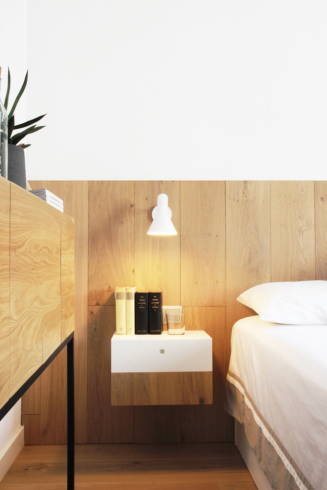 Modelo de dormitorio principal moderno pequeño con paredes blancas y suelo de madera clara