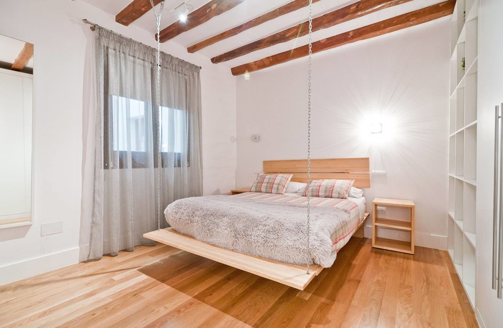 This is an example of a large scandinavian master bedroom in Madrid with white walls, light hardwood flooring and no fireplace.