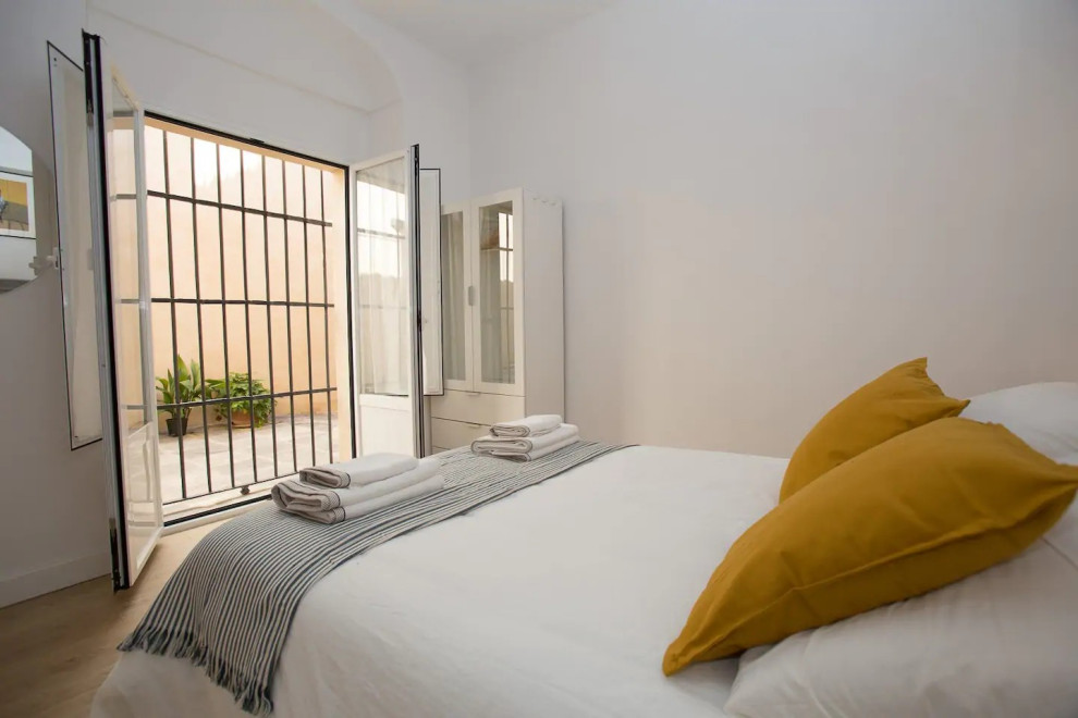 Imagen de dormitorio principal ecléctico pequeño con paredes blancas, suelo laminado y suelo beige
