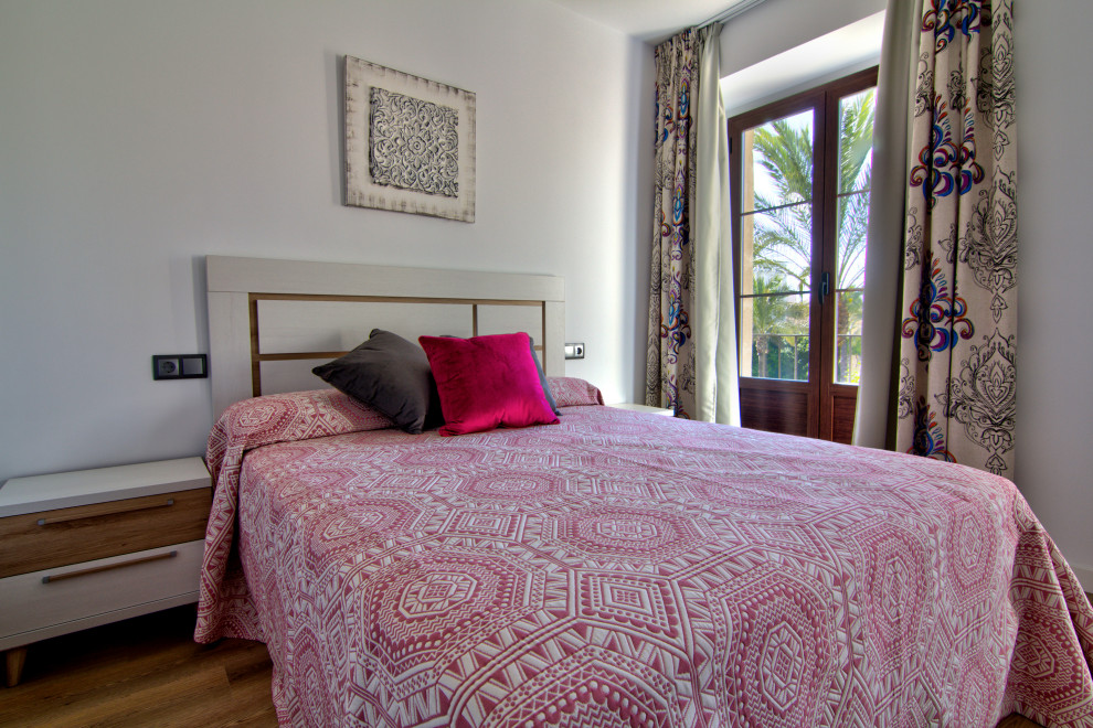 Пример оригинального дизайна: маленькая хозяйская спальня в стиле фьюжн с белыми стенами, полом из ламината и коричневым полом для на участке и в саду