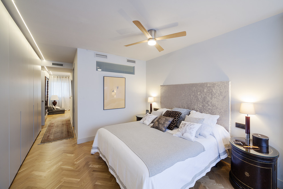 Mittelgroßes Modernes Hauptschlafzimmer ohne Kamin mit weißer Wandfarbe, braunem Holzboden und braunem Boden in Madrid