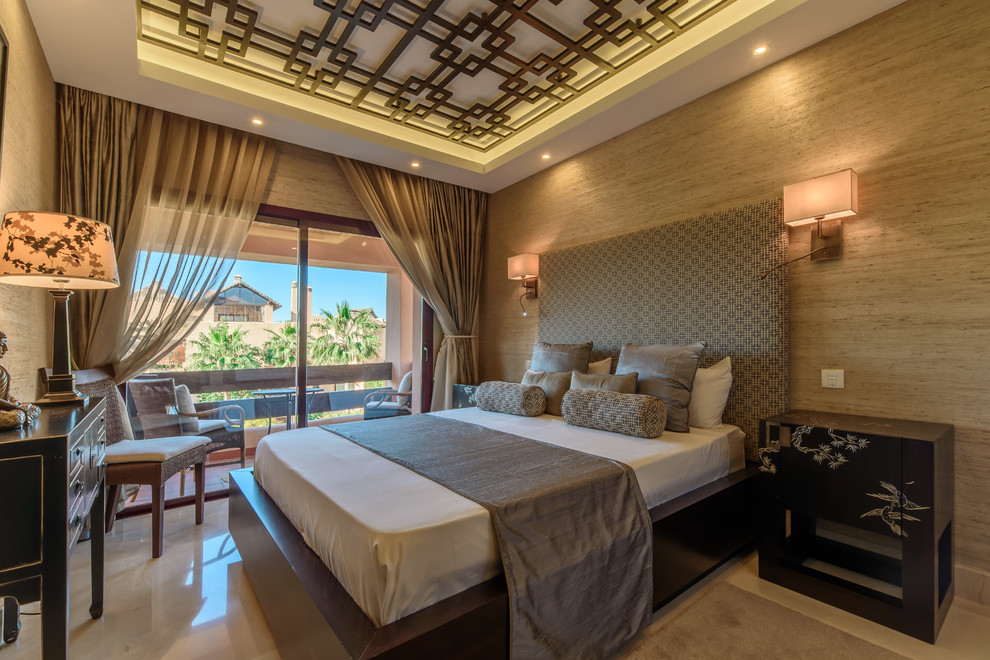 Large world-inspired master bedroom in Malaga with beige walls, marble flooring and beige floors.