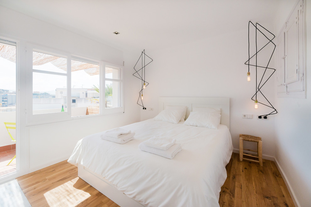 Example of a mid-sized danish master medium tone wood floor bedroom design in Barcelona with white walls and no fireplace