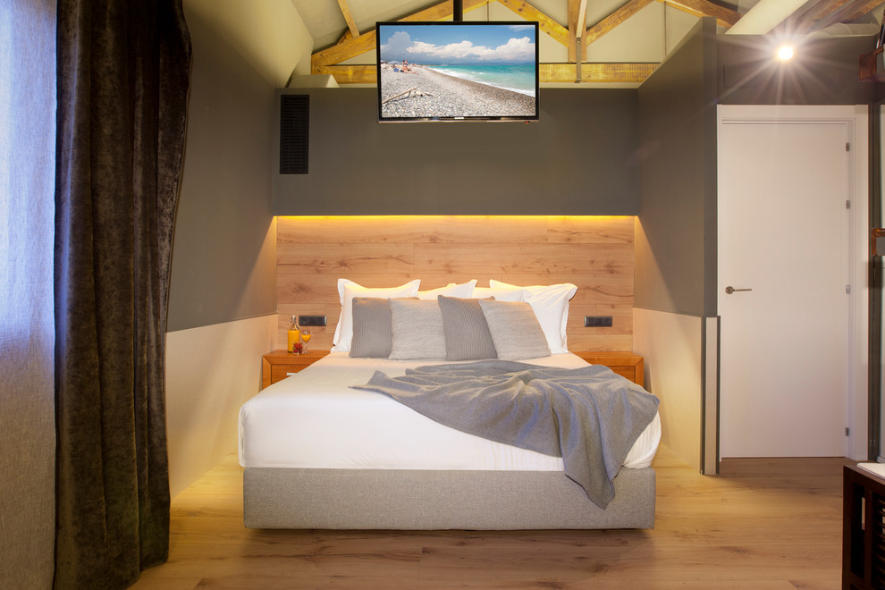 Imagen de dormitorio principal actual de tamaño medio sin chimenea con paredes grises y suelo de madera en tonos medios