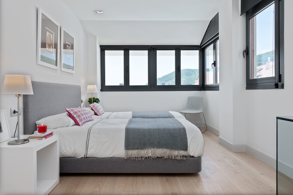Cette photo montre une chambre d'amis tendance de taille moyenne avec un mur blanc et un sol en bois brun.