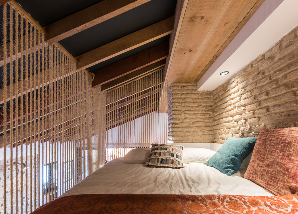 Example of a small tuscan loft-style bedroom design in Seville with beige walls and no fireplace