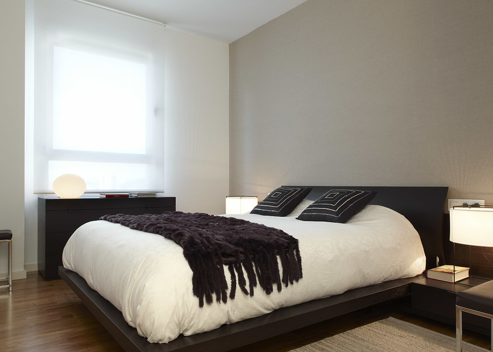 Diseño de dormitorio principal minimalista de tamaño medio sin chimenea con paredes blancas y suelo de madera en tonos medios