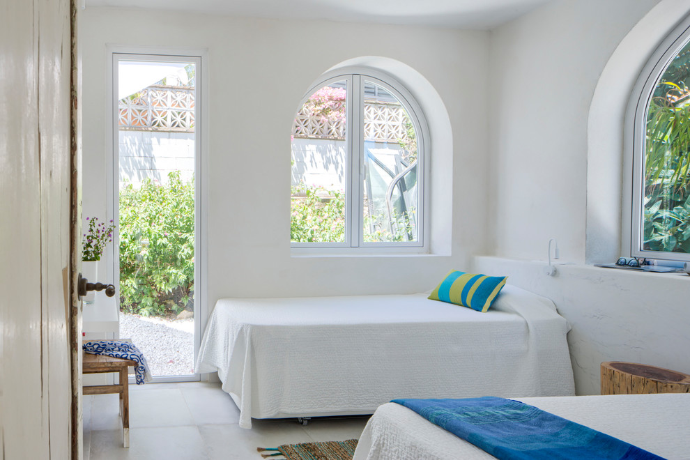 Diseño de dormitorio principal mediterráneo de tamaño medio con paredes blancas, suelo de baldosas de cerámica y suelo blanco