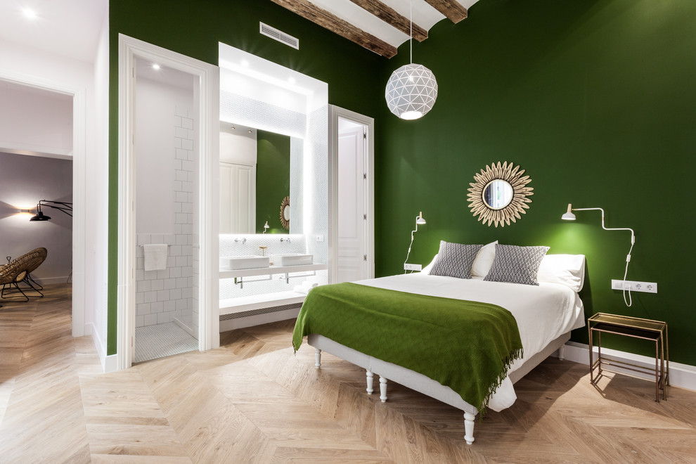 Cette photo montre une grande chambre parentale tendance avec un mur vert et un sol en bois brun.