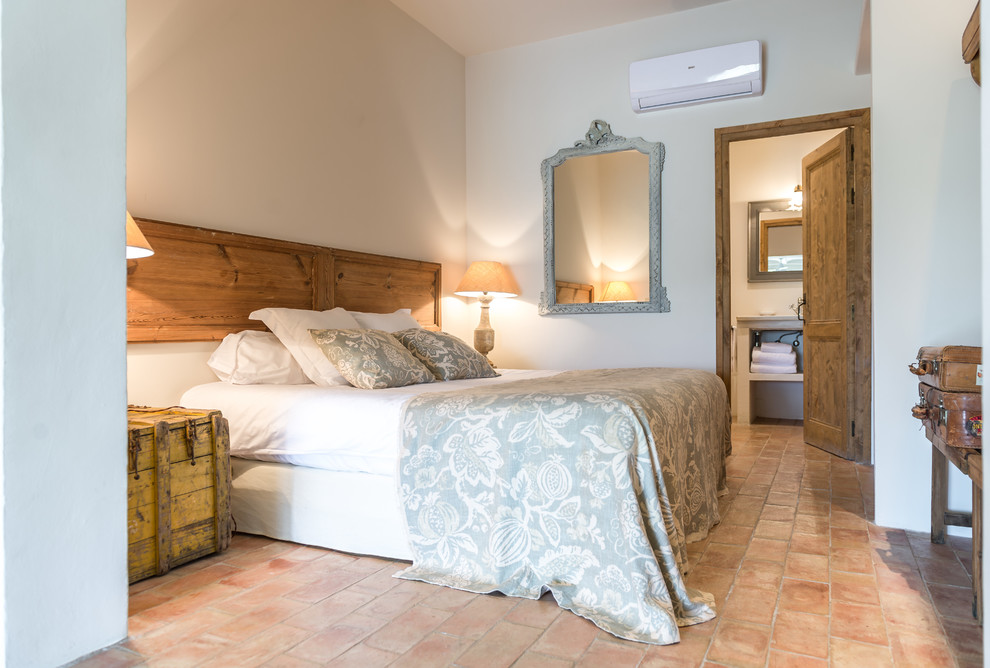 Foto de dormitorio principal rural de tamaño medio sin chimenea con paredes blancas y suelo de baldosas de terracota
