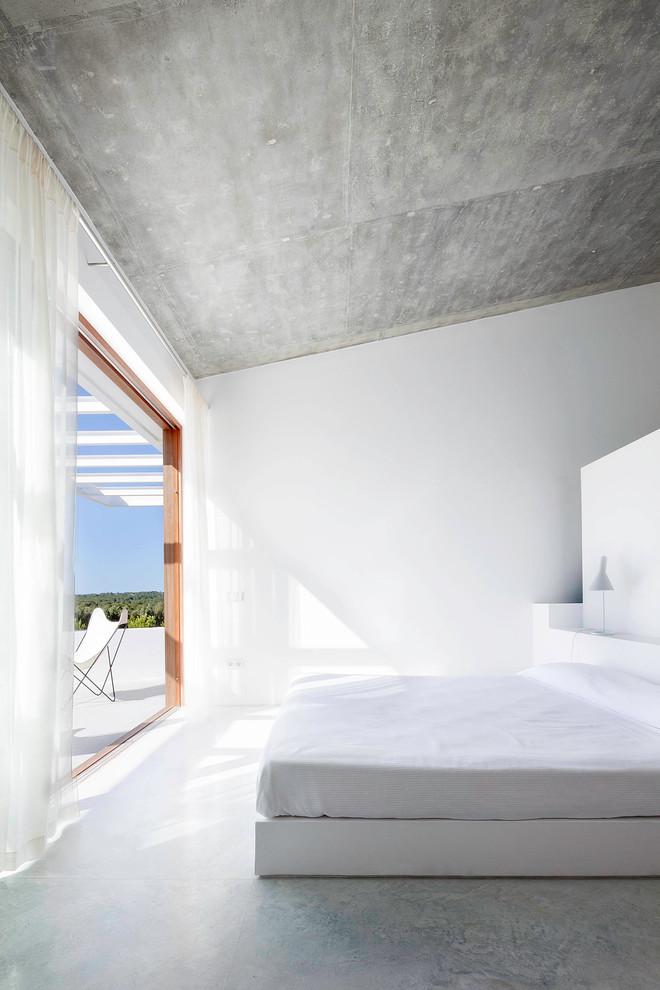 Großes Mediterranes Hauptschlafzimmer ohne Kamin mit weißer Wandfarbe und Betonboden in Sonstige