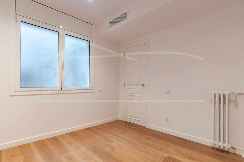 Imagen de habitación de invitados minimalista de tamaño medio con paredes blancas, suelo de madera en tonos medios y suelo marrón