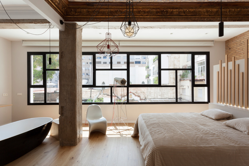Imagen de dormitorio principal actual grande con paredes blancas, suelo de madera en tonos medios y suelo beige