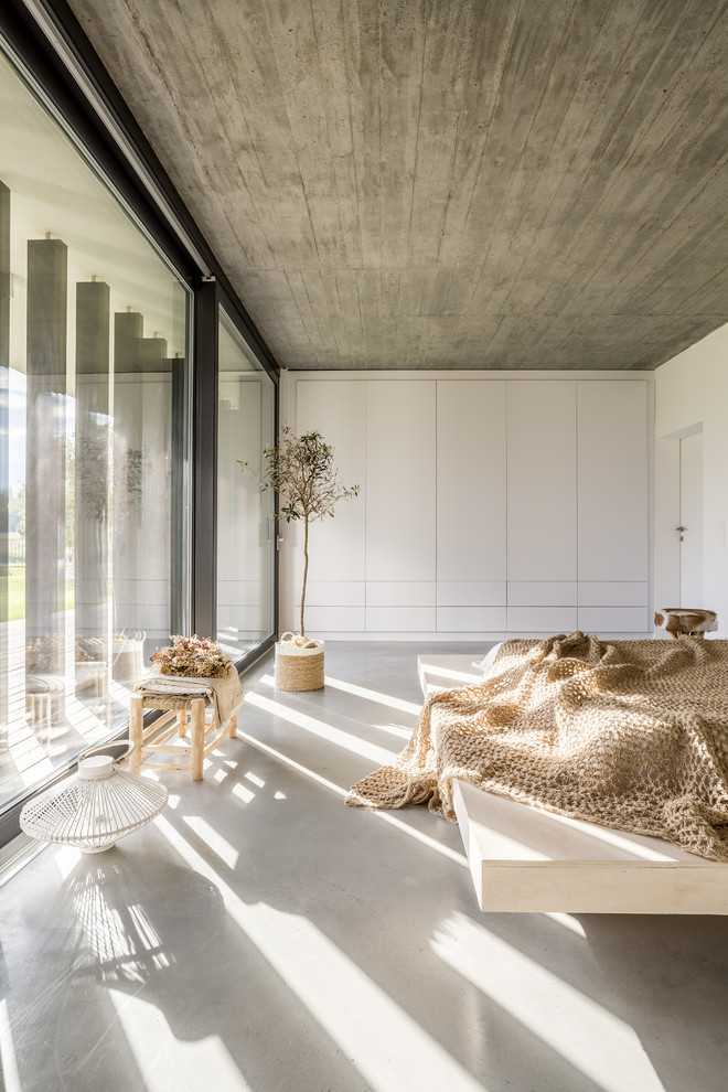 Idées déco pour une chambre moderne avec un mur blanc, sol en béton ciré et un sol gris.