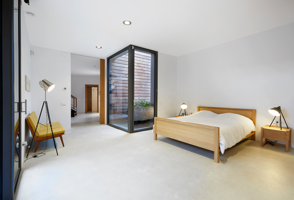 Contemporary master bedroom in Other with white walls, concrete flooring and grey floors.