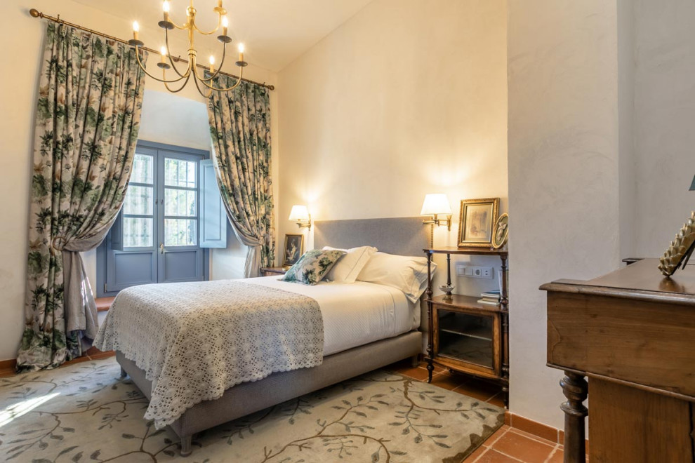 Mediterranes Schlafzimmer mit weißer Wandfarbe und braunem Boden in Sonstige