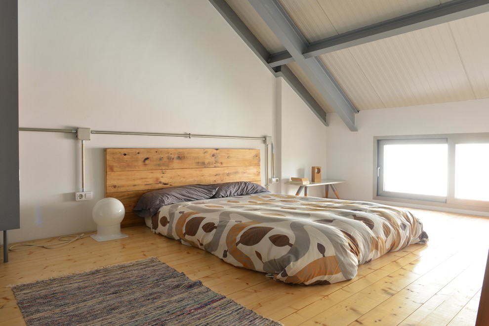 Cette image montre une chambre parentale nordique de taille moyenne avec un mur blanc, un sol en bois brun et aucune cheminée.