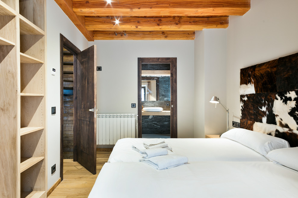 Mittelgroßes Uriges Hauptschlafzimmer ohne Kamin mit weißer Wandfarbe und braunem Holzboden in Barcelona