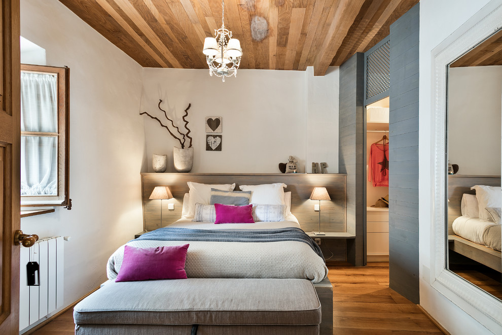 Exemple d'une chambre parentale grise et rose nature de taille moyenne avec un mur blanc, un sol en bois brun et aucune cheminée.