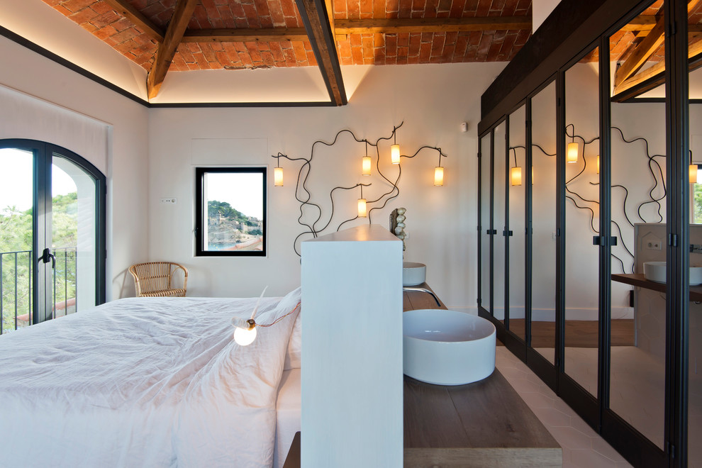 This is an example of a medium sized mediterranean master bedroom in Barcelona with white walls, medium hardwood flooring, no fireplace and brown floors.