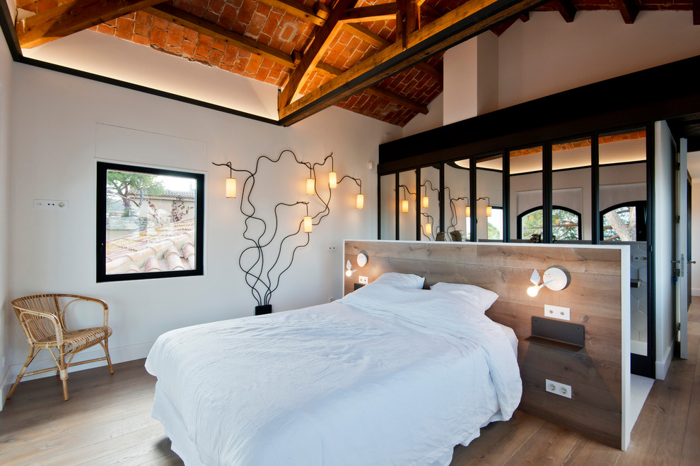 Mittelgroßes Mediterranes Hauptschlafzimmer ohne Kamin mit weißer Wandfarbe, braunem Holzboden und braunem Boden in Barcelona