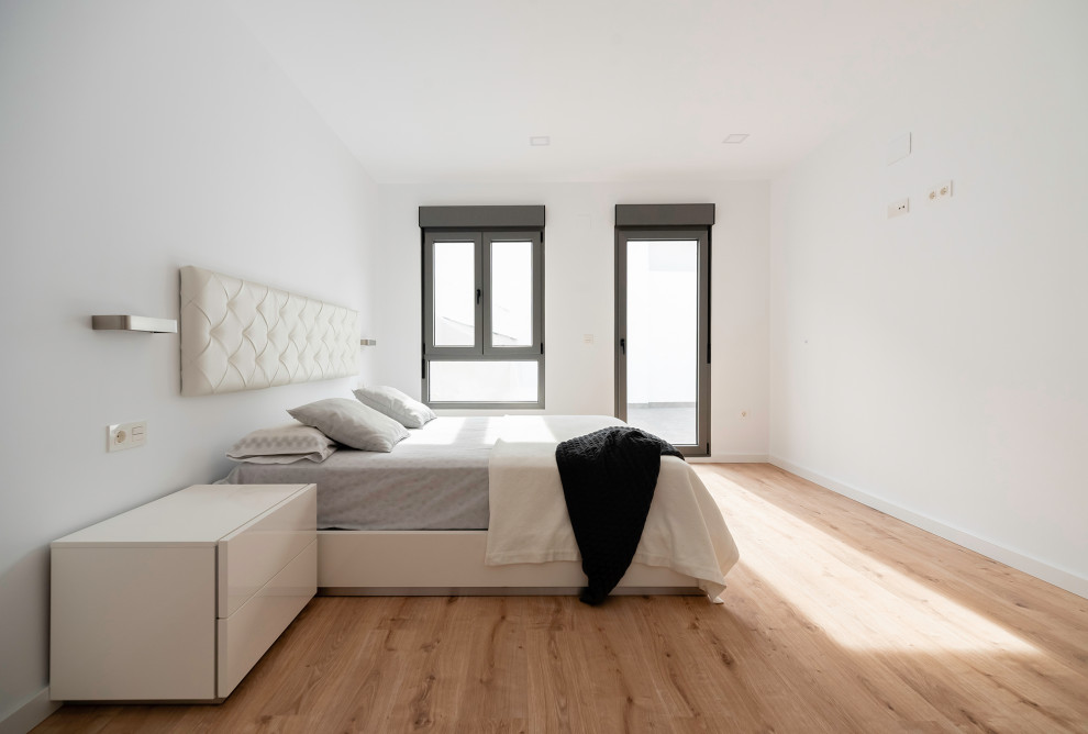 Contemporary master bedroom in Other with white walls and laminate floors.