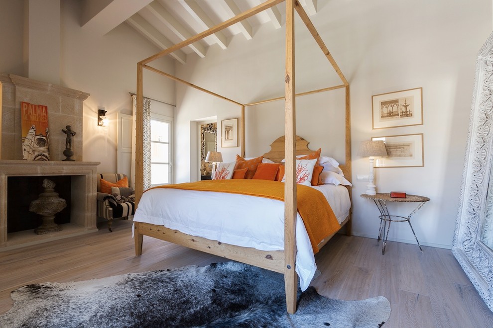Foto de dormitorio principal campestre grande con paredes blancas, suelo de madera clara, todas las chimeneas y marco de chimenea de piedra