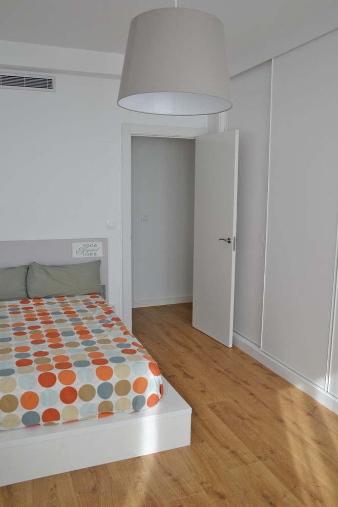 Foto de dormitorio principal escandinavo de tamaño medio sin chimenea con paredes blancas y suelo de madera en tonos medios