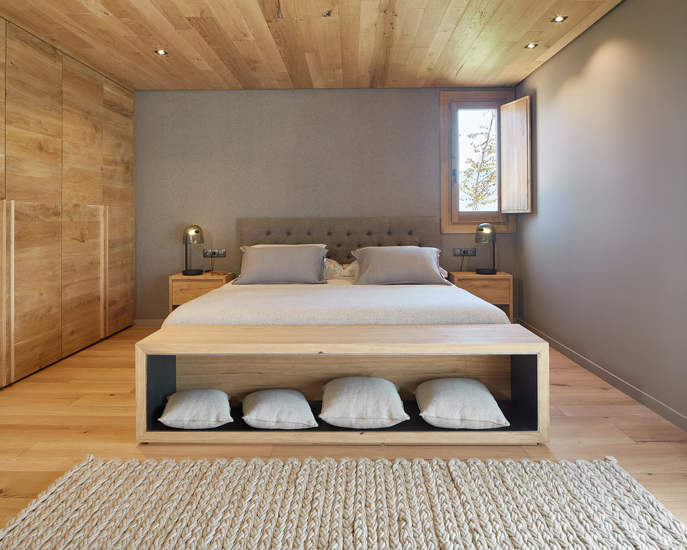 Modelo de dormitorio principal campestre grande con suelo de madera clara
