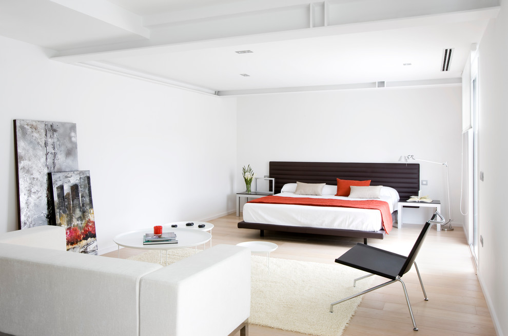 Imagen de dormitorio principal contemporáneo grande sin chimenea con paredes blancas y suelo de madera clara