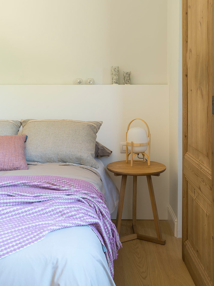 Imagen de habitación de invitados nórdica de tamaño medio sin chimenea con paredes blancas, suelo de madera en tonos medios y suelo marrón