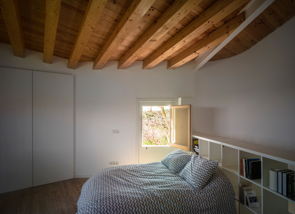 Réalisation d'une chambre parentale méditerranéenne de taille moyenne avec un mur blanc et un sol en bois brun.