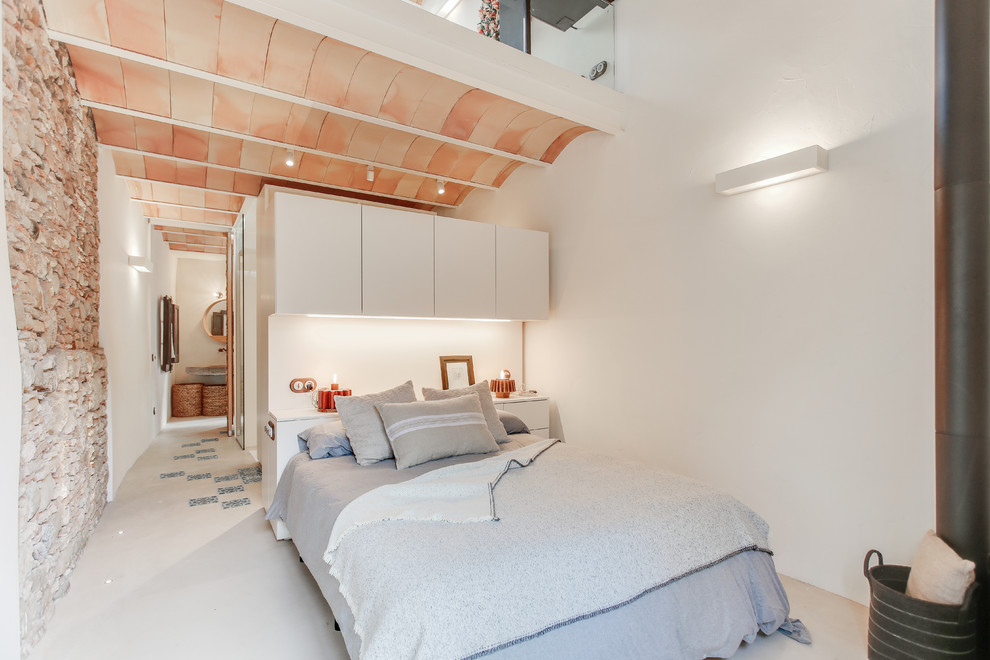 Mittelgroßes Mediterranes Schlafzimmer ohne Kamin, im Loft-Style mit weißer Wandfarbe, Betonboden und grauem Boden in Sonstige
