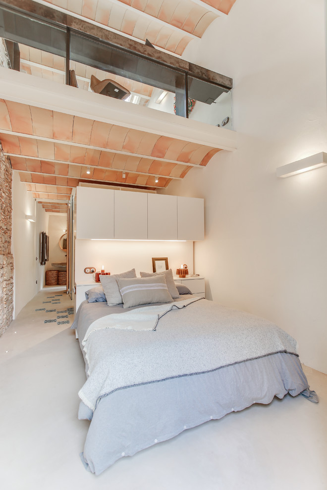 Idées déco pour une chambre mansardée ou avec mezzanine méditerranéenne de taille moyenne avec un mur blanc, sol en béton ciré et un sol gris.